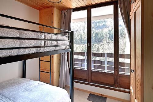 une chambre avec un lit superposé et une grande fenêtre dans l'établissement Le Cocoøn, balcon, vue station, à La Bresse