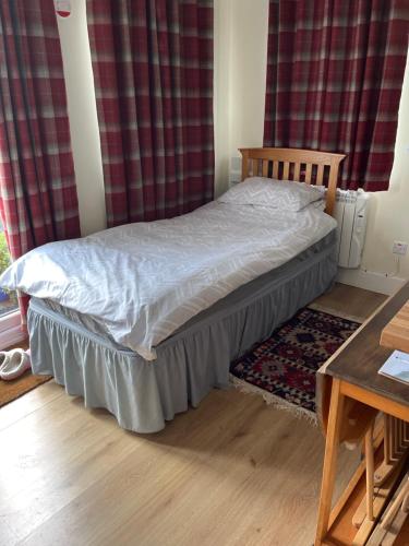 a small bed in a room with red curtains at The Cabin in Hockham