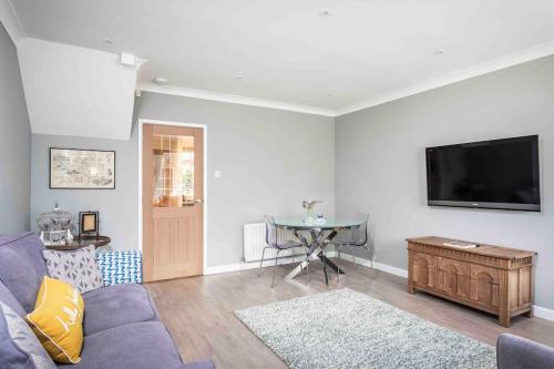 a living room with a couch and a tv on a wall at Lilliput Hideaway 5 mins from Sandbanks Beach in Parkstone