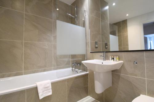uma casa de banho com um lavatório, uma banheira e um WC. em Tooley Street Apartments by Viridian Apartments em Londres