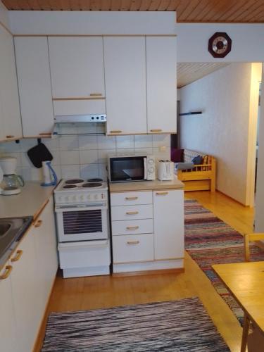 a kitchen with white cabinets and a stove top oven at Varakoti Iines in Loimaa
