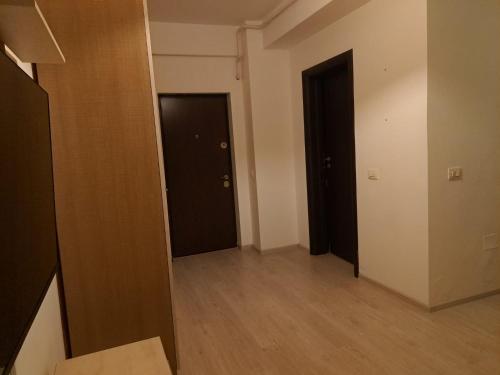 um corredor vazio com duas portas pretas e pisos de madeira em Zen Studio em Roşu