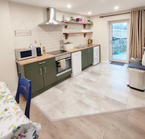 a kitchen with green cabinets and a tile floor at Unboring Holiday Let, Ballina, Mayo in Ballina
