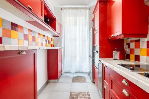 une cuisine rouge avec des placards rouges et une fenêtre dans l'établissement Coeur Camas, 10 mins du Vieux-Port, à Marseille