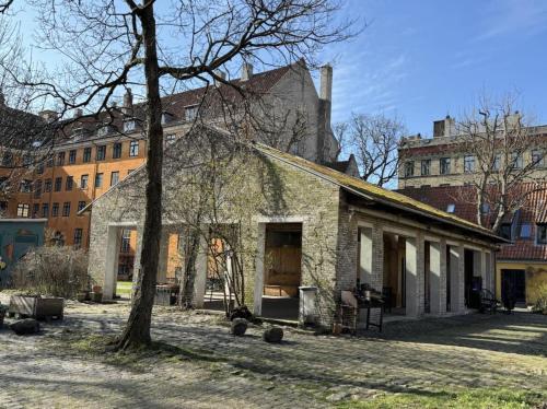 uma antiga casa de pedra com uma árvore e edifícios em ApartmentInCopenhagen Apartment 1594 em Copenhague