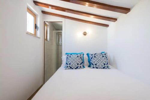 a bedroom with white walls and blue pillows on a bed at Bungalow Ubicación Ideal in San Bartolomé de Tirajana