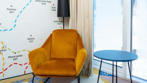 a yellow chair sitting next to a blue table at Aparthotel Biała Perła - Czarna Góra Resort, Sun & Snow in Sienna