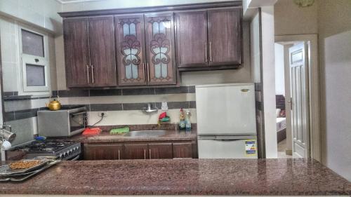 cocina con armarios de madera y nevera blanca en Lazorde Bay Apartment en El Alamein