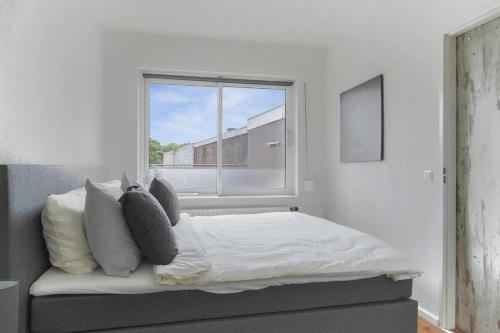 a bedroom with a bed with pillows and a window at Appartement Groot, Hartje Centrum, Colline's in Tilburg