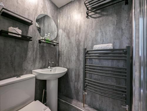 a bathroom with a sink and a toilet and a mirror at Cozy, Chic, Dairy Cottage near to Beach & Shops- Parking in Torquay