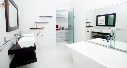 Baño blanco con 2 lavabos y espejo en JFT Jewels Guest House en East London