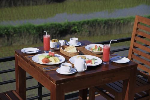 a wooden table with plates of food on it at Nang Ade Villa by Pramana Villas in Ubud