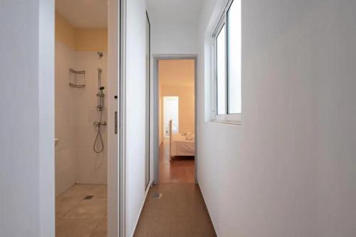 einen Flur mit einem Bad mit Dusche und einem Fenster in der Unterkunft Amplio Apartamento en el centro in San Bartolomé de Tirajana