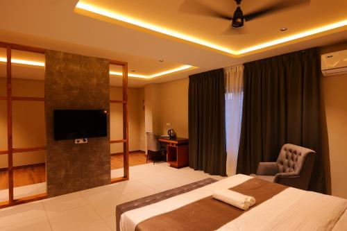 KānnangādHotel Classico International的配有床和电视的酒店房间