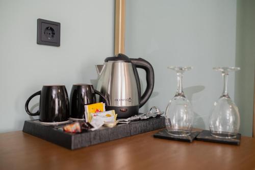 Aggelos Hotel في أليكساندروبولي: غلاية الشاي والأكواب على طاولة خشبية