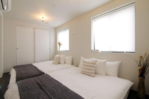 - une chambre avec un grand lit blanc et des oreillers dans l'établissement bHOTEL Komachi - New Apt for 6ppl near PeacePark, à Hiroshima