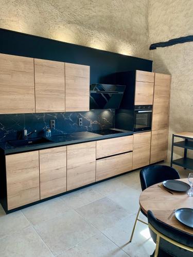 une cuisine avec des placards en bois et une table dans l'établissement L'Alternative - Gîte pour 4 personnes - Bruniquel, à Bruniquel