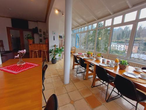 una sala da pranzo con tavoli, sedie e finestre di Gite Villa le Monde - La Roche-en-Ardenne a La-Roche-en-Ardenne