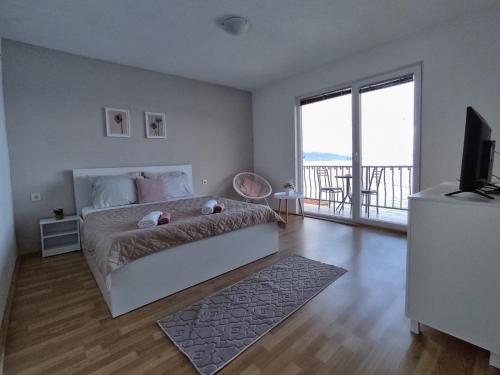 a white bedroom with a bed and a balcony at Apartment Polkaposki Trpejca in Trpejca