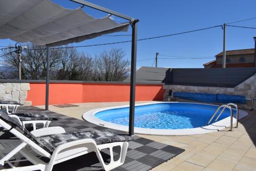 een zwembad met stoelen en een parasol op een patio bij Holiday House Risika Seaview in Risika