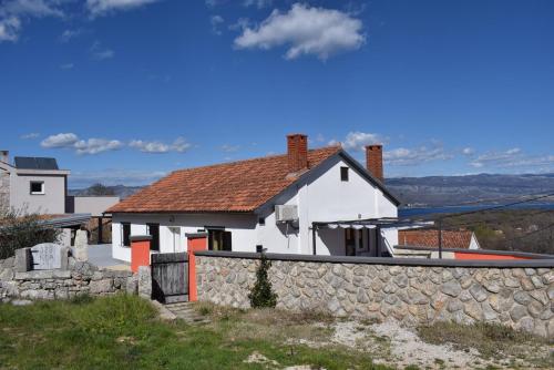 een wit huis met een stenen muur bij Holiday House Risika Seaview in Risika