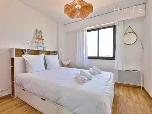 a white bedroom with a large white bed with towels on it at Appartement au pied de la plage, vue imprenable sur la mer in Les Sables-dʼOlonne