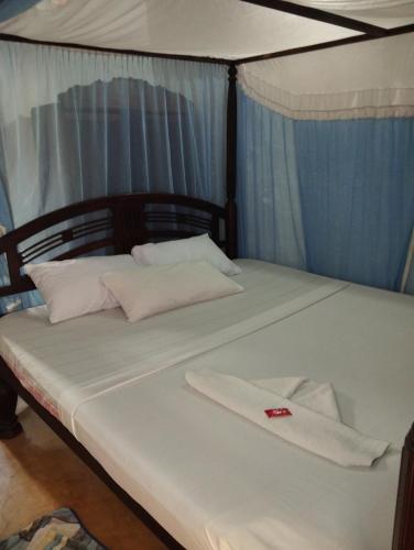 Una cama con sábanas blancas y almohadas. en Subira Guest House, en Lamu