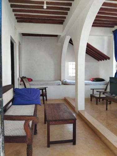 a room with two beds and a table and chairs at Subira Guest House in Lamu