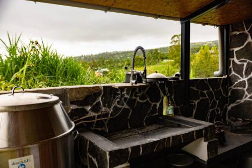 a stone kitchen with a sink and a window at Le muguet sauvage in Le Tampon