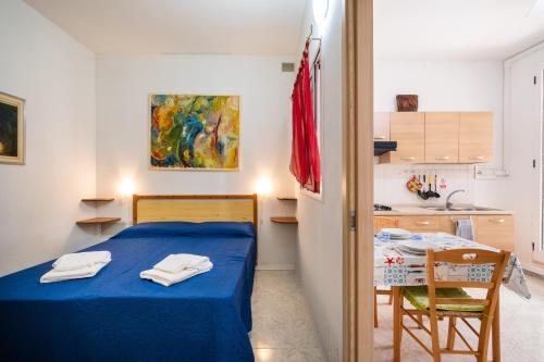 a small bedroom with a blue bed and a kitchen at Villa Ada Depandance 1 in Punta Prosciutto