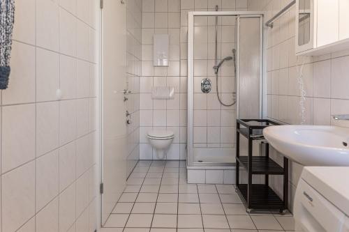 a white bathroom with a toilet and a sink at 50189 Meermomente in Harlesiel