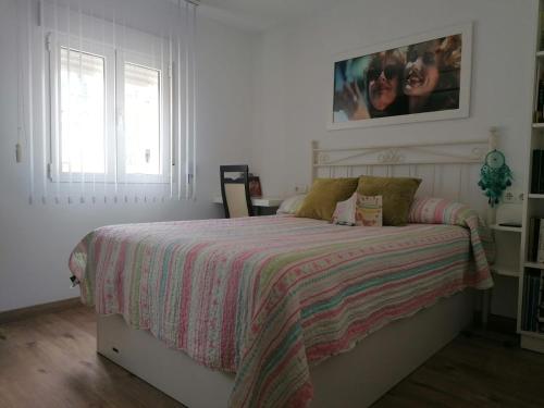 a white bedroom with a bed with a striped blanket at Casa Paraiso in Almería