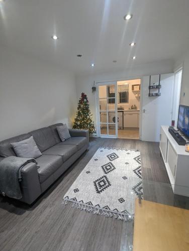 a living room with a couch and a christmas tree at Modern ground floor flat in Cranford