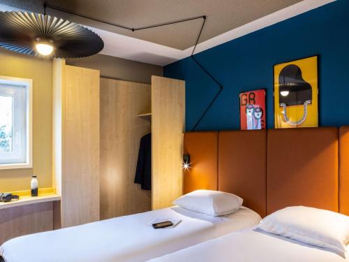 um quarto com 2 camas e uma parede azul em ibis Aulnay Paris Nord Expo em Aulnay-sous-Bois