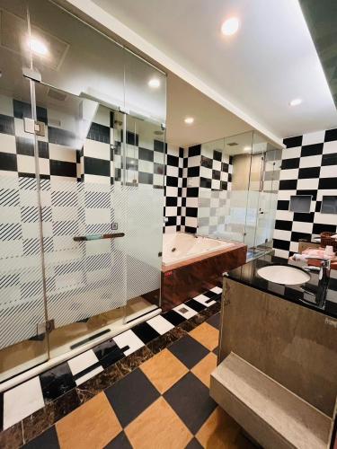 a bathroom with a glass shower and a checkerboard floor at Walker Motel in Taipei