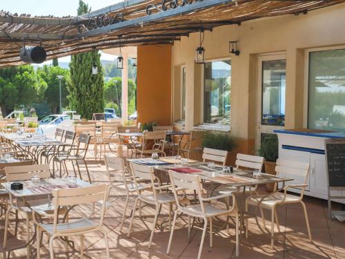 eine Gruppe von Tischen und Stühlen auf einer Terrasse in der Unterkunft ibis La Ciotat in La Ciotat