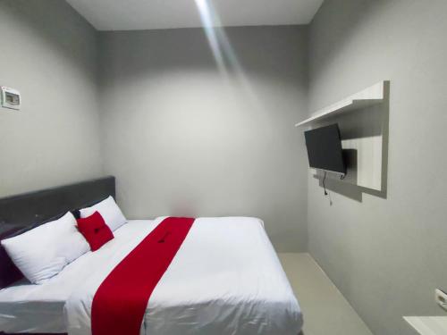 um quarto com uma cama com uma fita vermelha em RedDoorz Near Rumah Sakit Soewandhie em Surabaia