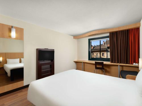 um quarto de hotel com uma cama e uma televisão em Ibis Budapest Heroes Square em Budapeste