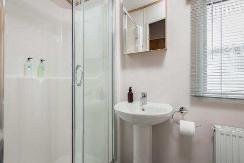 uma casa de banho branca com um lavatório e um chuveiro em Lodge 10 The Silverdale Close to St Andrews em St Andrews