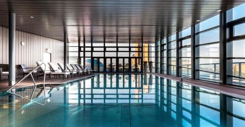 uma piscina num edifício com cadeiras e janelas em Grand Hyatt Berlin em Berlim