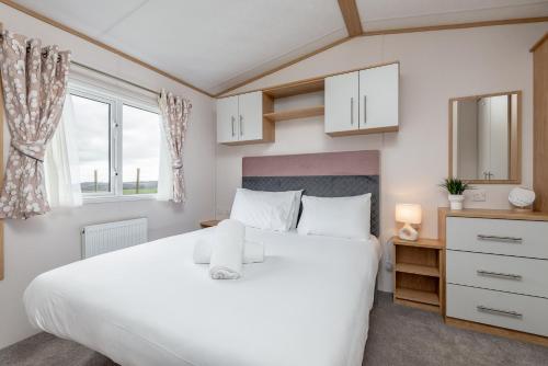 um quarto com uma grande cama branca e janelas em Lodge 10 The Silverdale Close to St Andrews em St Andrews