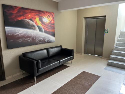 a black leather couch in a lobby with a painting at Apartament Planeta 106 - tylko 100 m od plaży in Mielno