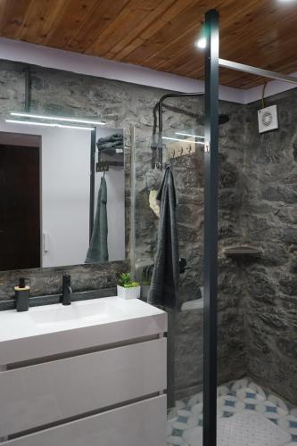 een badkamer met een witte wastafel en een stenen muur bij Casa do Lombo in Machico