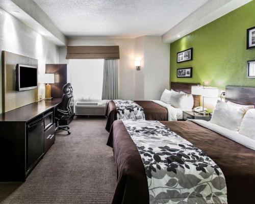 a hotel room with two beds and a desk at Sleep Inn Fort Pierce I-95 in Fort Pierce