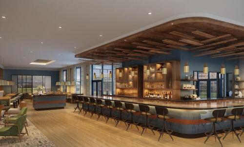 a lobby with a bar with chairs and tables at Hotel Indigo Irving - Las Colinas, an IHG Hotel in Irving