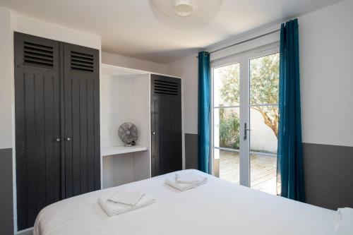 a bedroom with a white bed and a window at BEACH HOUSE in Les Grenettes