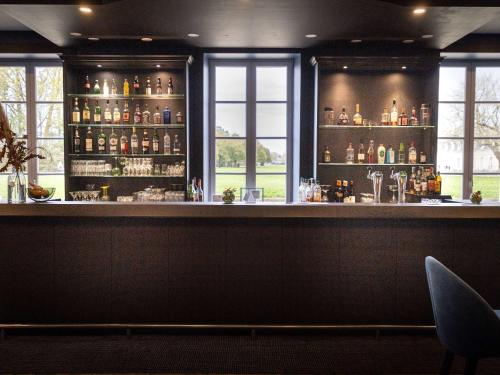 a bar in a restaurant with a counter and windows at Hôtel Mercure Rochefort La Corderie Royale in Rochefort