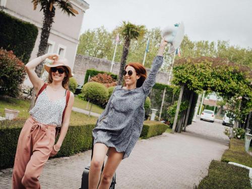 two women walking down a sidewalk holding a bird in the air at Hôtel Mercure Rochefort La Corderie Royale in Rochefort