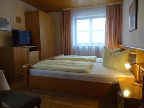 ein kleines Schlafzimmer mit einem Bett und einem Fenster in der Unterkunft Gästehaus Böck in Roßhaupten