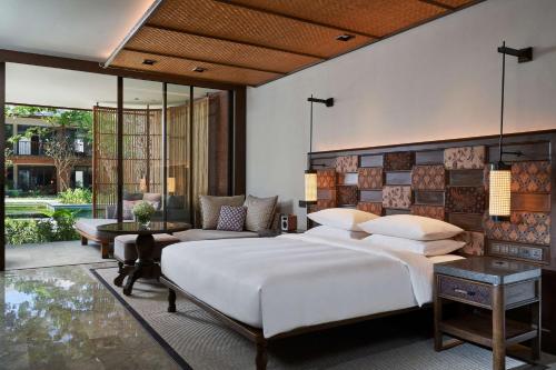 Andaz Bali - a Concept by Hyatt في سانور: غرفة نوم بسرير كبير وأريكة